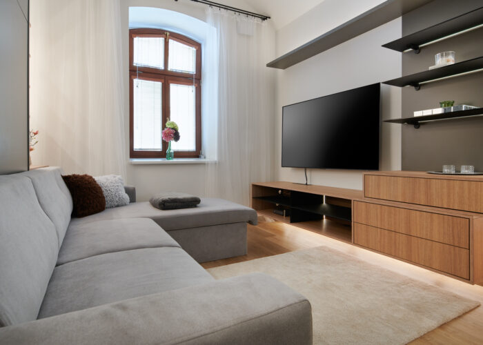 Sklopná postel s lenoškou v garsonce se sklopeným stropem - Prohlédněte si realizaci bílé vestavěné skříně s integrovanou televizí. Elegantní a funkční řešení úložných prostor od Woodface.