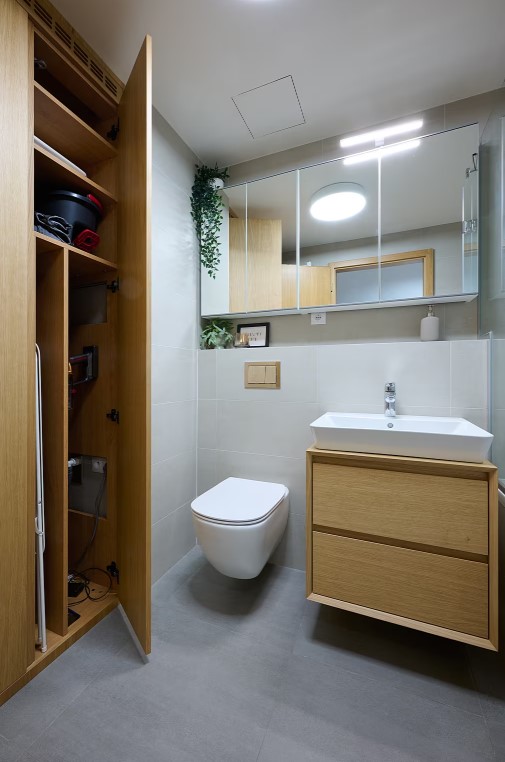 Koupelnový nábytek v lakované přírodní dýze skrývá pračku, sušičku i další předměty nutné pro úklid.